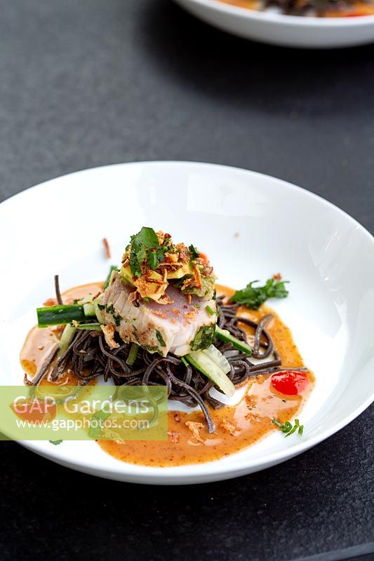 Garden table in Manoj Malde roof garden with food served - seared tuna and noodles.