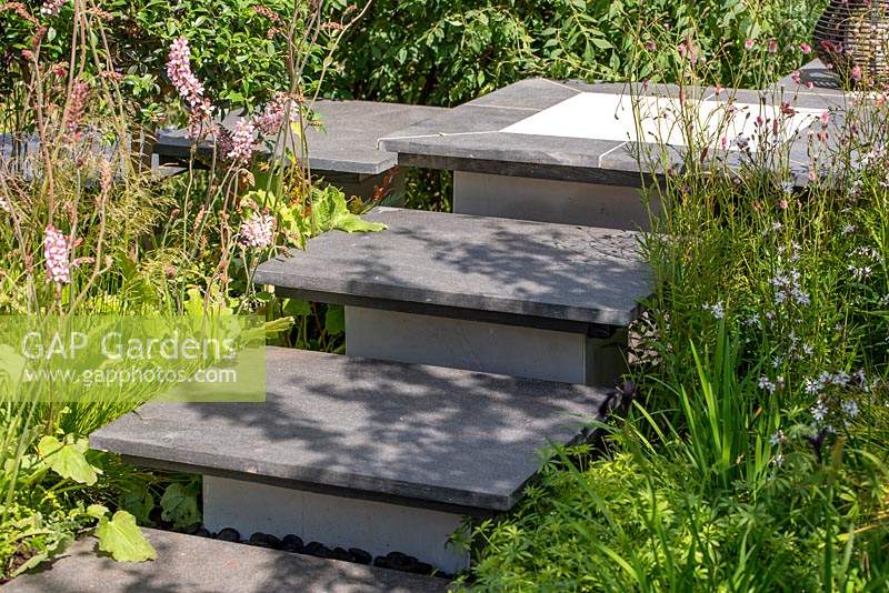 Paved steps lead through beds of herbaceaous planting. RHS Hampton Court Palace Flower Festival 2019.