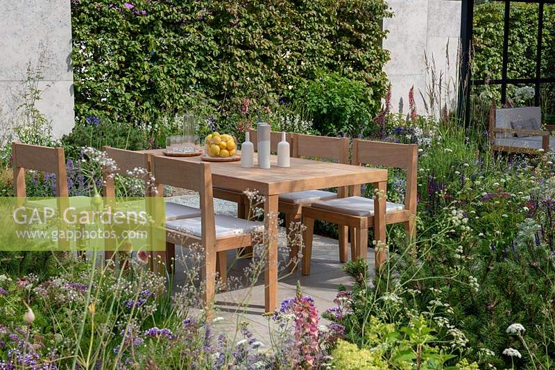 Dining area surrounded by herbaceous planting with Pinus mugo - The Viking Cruises Lagom Garden, RHS Hampton Court Palace Flower Festival 2019