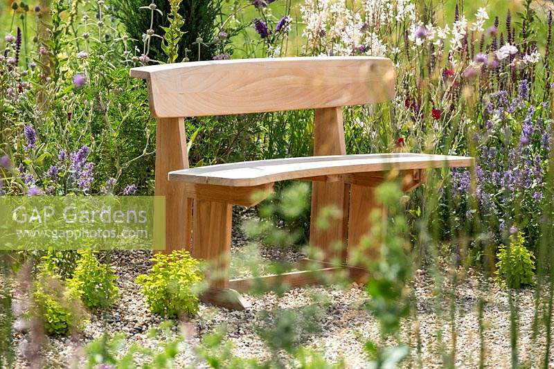 A curved wooden seat bench in The Drought Tolerant Garden at the RHS Hampton Court Palace Garden Festival 2019.