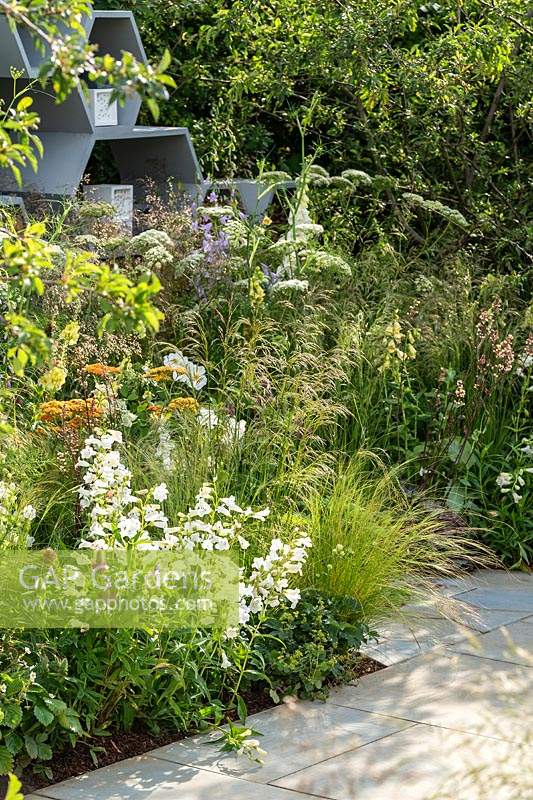 The Urban Pollinator garden at the RHS Hampton Court Palace Garden Festival 2019. A garden planted to attract wildlife - A contemporary honeycomb shapes feature in a wall designed to be a habitat for insects. Sponsor: Warner's Distillery