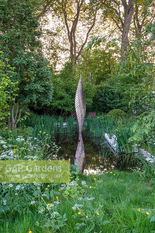 Bronze shard by David Harber set in a pool surrounded by Iris pseudacorus and wild planting of Cow Parsley- The Savills and David Harber Garden, RHS Chelsea Flower Show 2019.