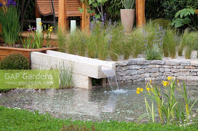 The Harmonious Garden of Life, the stone canal brings water from a trough where it is filtered which is planted by Iris pseudocorus and Iris laevigata to the pond, it is bordered by Stipa tenuifolia and a clover lawn. Sponsors: Mr and  Mrs Cawthorn, Margheriti Piante.