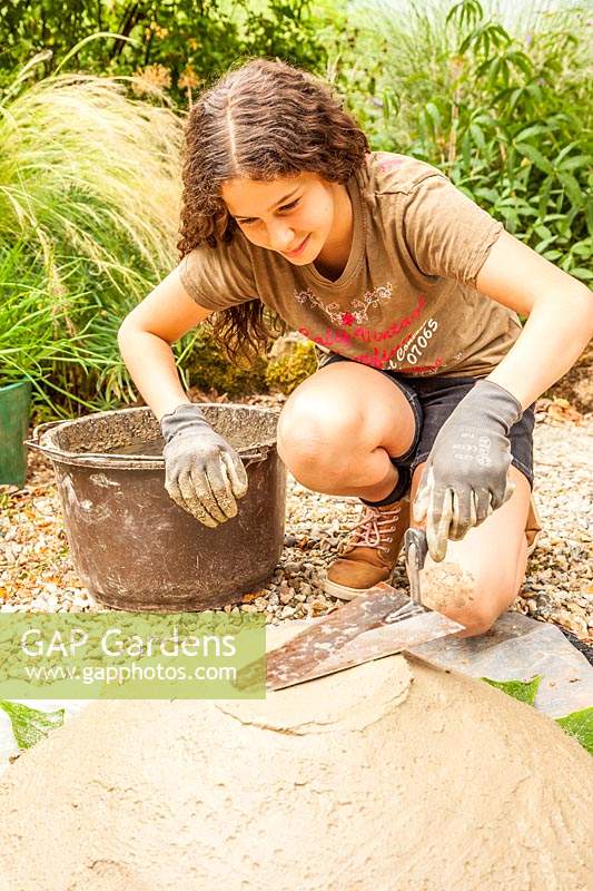 Young girl shaping the base of concrete bird bath - Step-by-step. How to make a concrete bird bath.