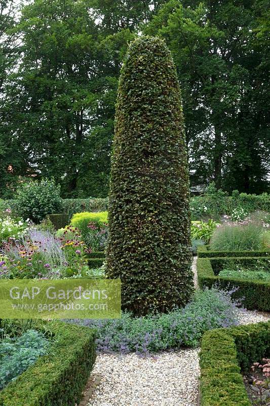 Huge topiary column at intersection of paths in formal garden