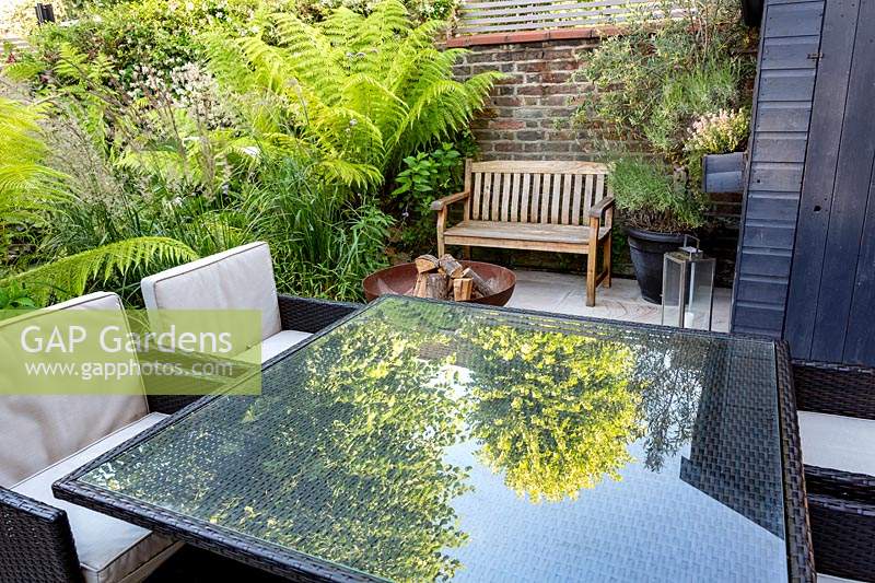 Seating and dining patio area in small shade tolerant garden in London with a green theme. Planting includes Calamagrostis x acutiflora Karl Foerster, Dicksonia antarctica.