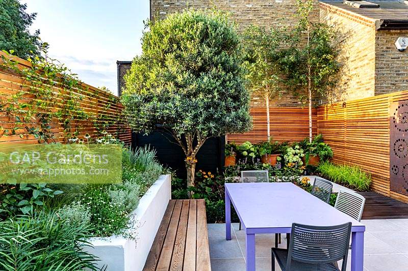 Small contemporary London garden with raised bed, bespoke garden seating with table and chairs