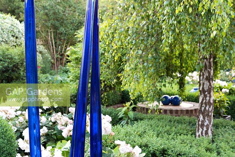 Blue glass sculptures in front of Rosa 'Penelope' - Rose 