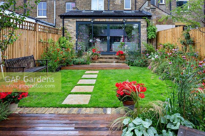 Contemporary garden in West London with wood decking and herbaceous borders, with view towards house