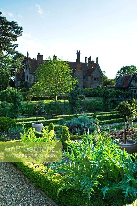 A formal garden with clipped Buxus hedges and gravel pathways - Hindringham Hall, Norfolk. 