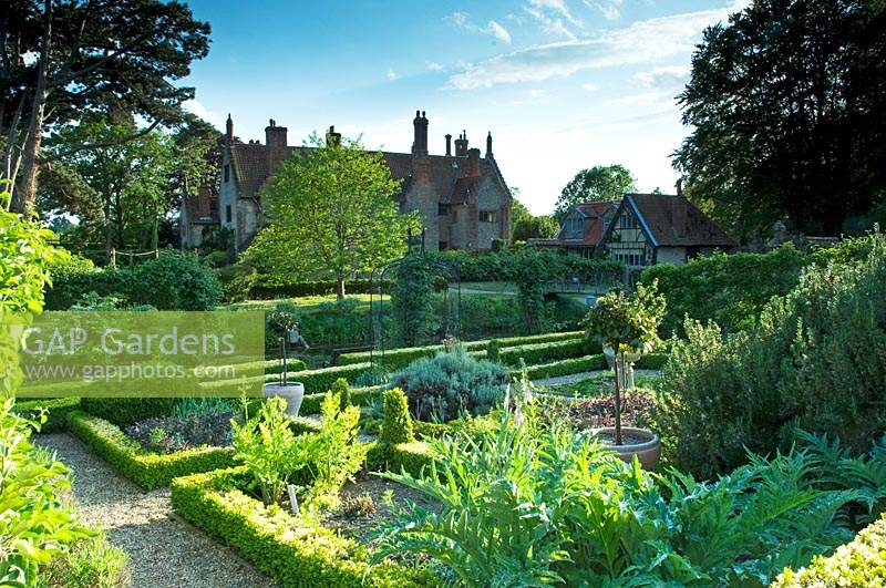View of formal garden with clipped Buxus - Box - edging and gravel pathways, view of hall beyond
