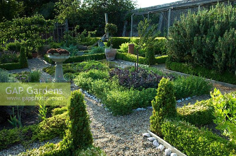Herb parterre in the centre of formal walled vegetable and fruit garden, beds separated by gravel paths