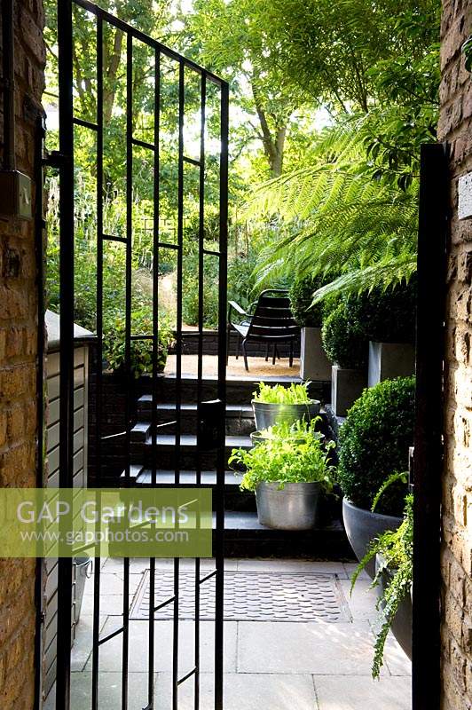 Modern black gateway with view through to an urban garden