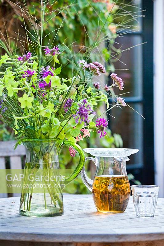 Herbal ice tea and bouquet of cut flowers in a vase, on a table