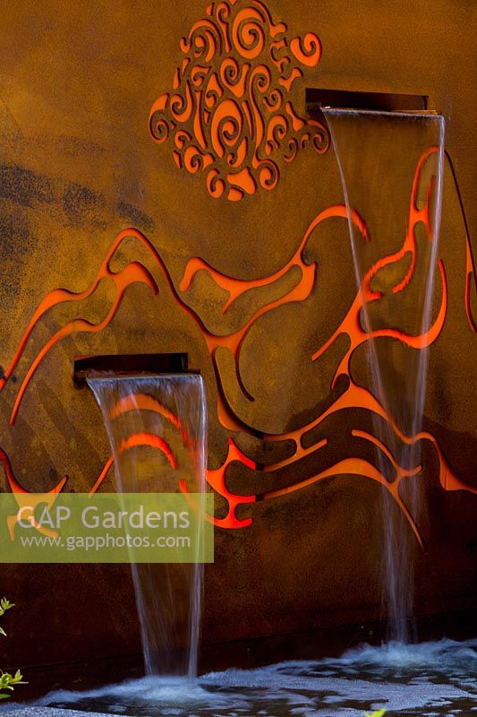 Freestanding rusty corten steel fountain, featuring internally lit laser cut pattern representing mountains, with one rill.