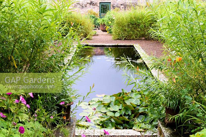 Formal pond in the walled garden surrounded by a willow hedge at Broadwoodside, Gifford, East Lothian in Scotland.