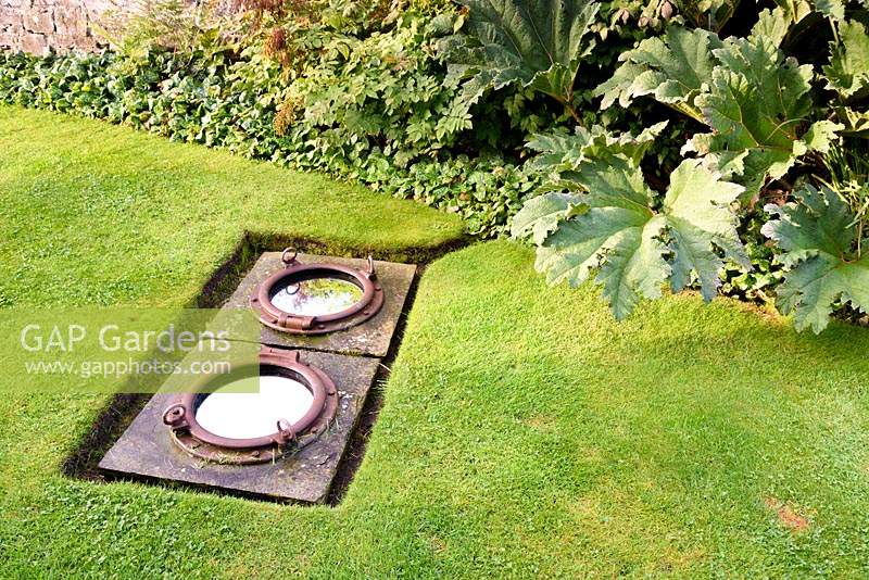 Ship's portholes inset with mirror and set into the lawn at Broadwoodside, Gifford, East Lothian.