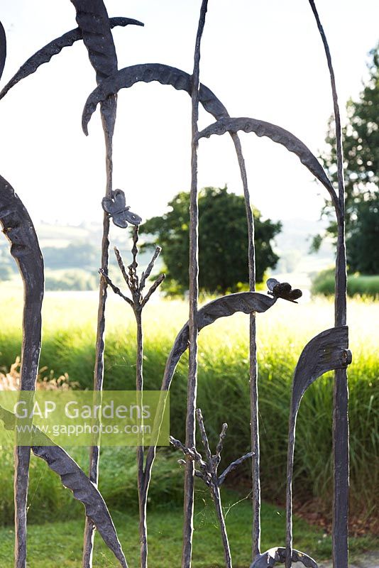 Decorative wrought iron gate picturing grasses and butterflies 
