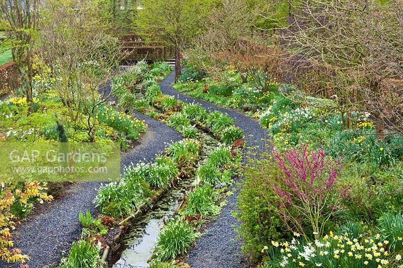 View from above to spring borders with stream and gravel paths.