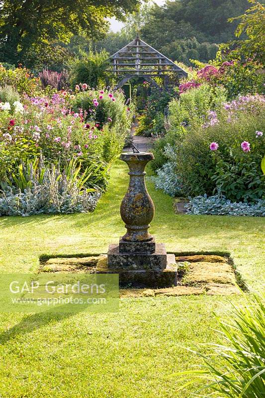  The sundial and wooden pergola in Sundial Garden. Wollerton Old Hall Garden, Shropshire, UK  Planting includes: Japanese anemones, Dahlias, Phlox paniculata, Stachys byzantina and Salvia microphylla