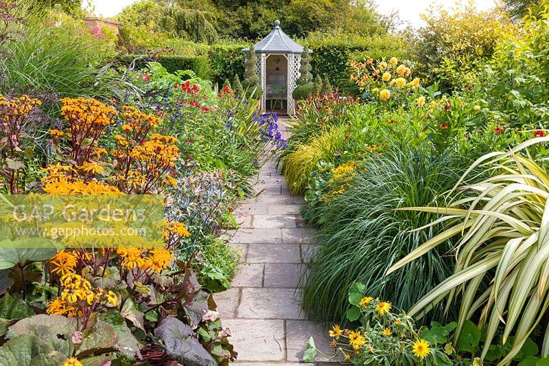 The Lanhydrock Garden, Wollerton Old Hall Garden, Shropshire, UK. View of the Summerhouse. Planting includes Phormiums, Ligularia, Dahlias and Agapanthus