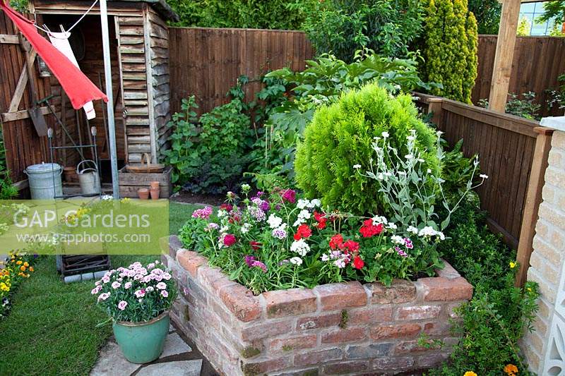 Raised brick bed with dianthus and geraniums in the 1960's Anniversary Garden at BBC Gardener's World Live 2017.