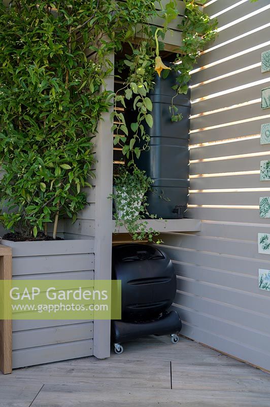 Outdoor room shelving units hiding compost bin and water tank - The Year of Green Action Garden - RHS Hampton Court Palace Garden Festival 2019. Sponsors: Defra.