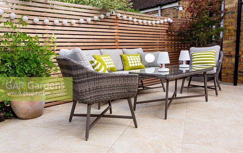 London contemporary garden patio with modern garden sofa, chairs  and table on patio with cedar batten trellis fencing behind.