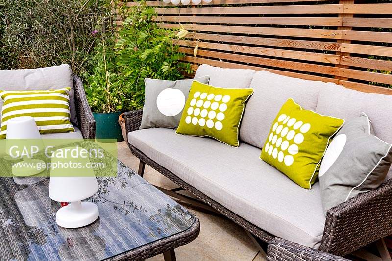 London contemporary garden with modern garden sofa, chairs and table on patio with cedar batten trellis fencing behind.