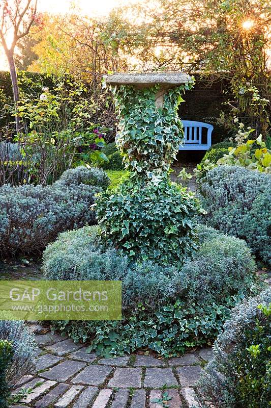 Circular patio with stone urn covered with ivy.