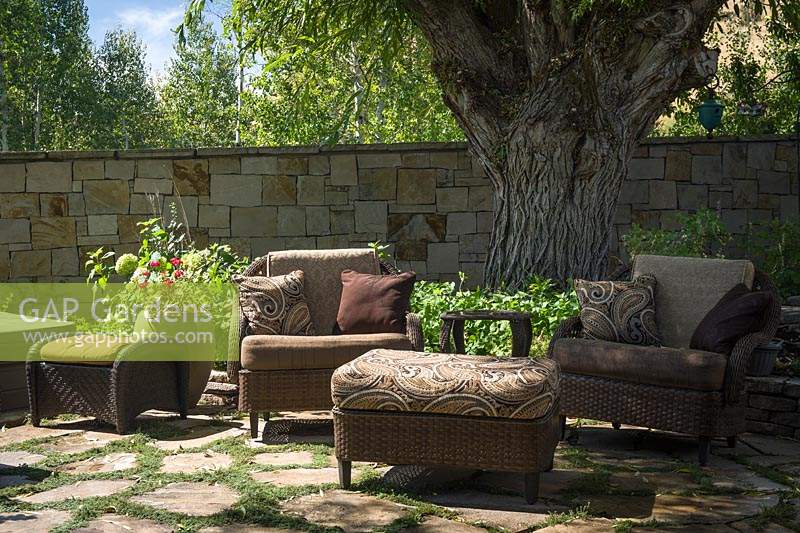 Outdoor wicker seating on flagstone patio under large tree