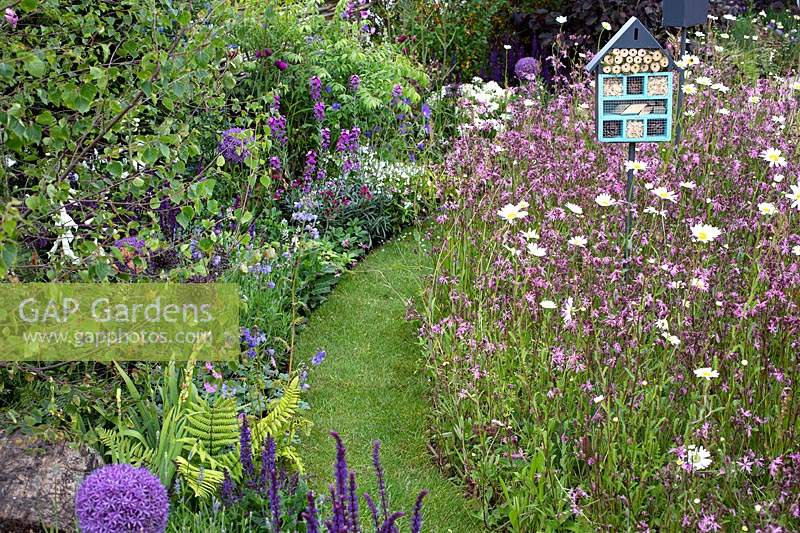'RHS Garden for Wildlife Wild Woven' - RHS Chatsworth Flower Show 2019 - winding grass path through wildflower borders.