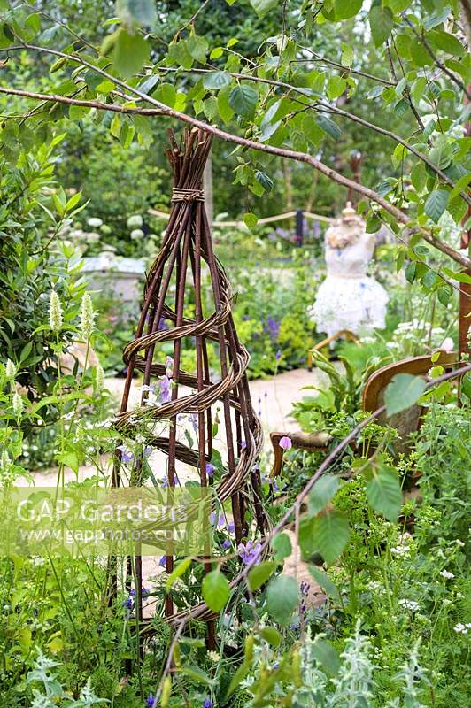 Hand-woven willow obelisk to support flowering sweet peas - Lathyrus odoratus. The Naturecraft Garden. RHS Hampton Court  Palace Garden Festival, 2019.   