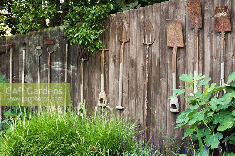 Vintage garden tools hung on a wooden fence