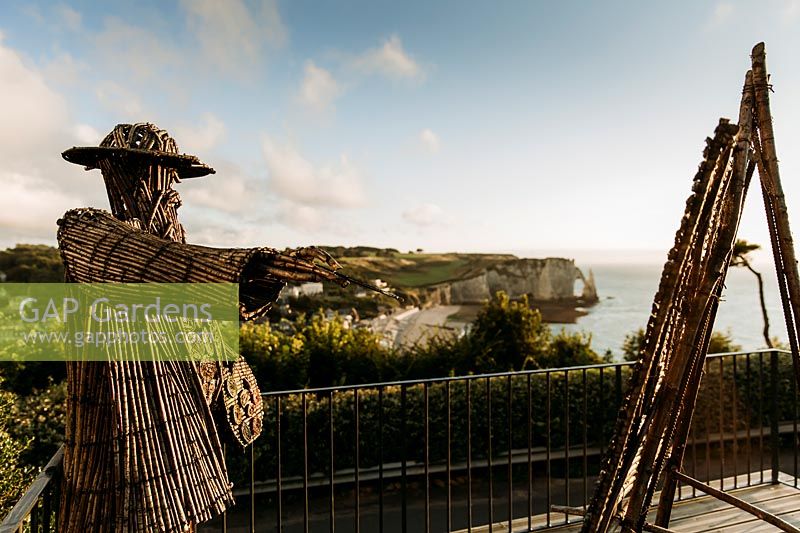 Jardin Impressions with wicker statue of Claude Monet with easel overlooking the sea. Les Jardins d Etretat, Normandy, France