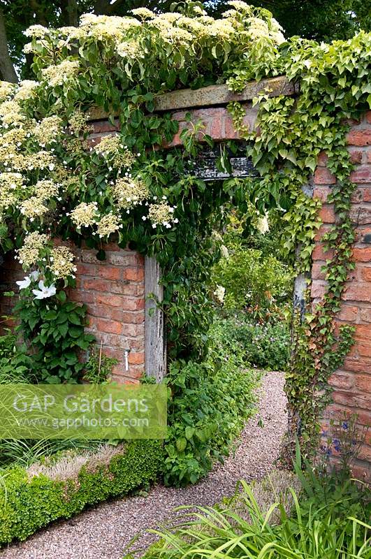 View through gate in brick wall to The Croft Garden at Wollerton Old Hall Garden, Shropshire.