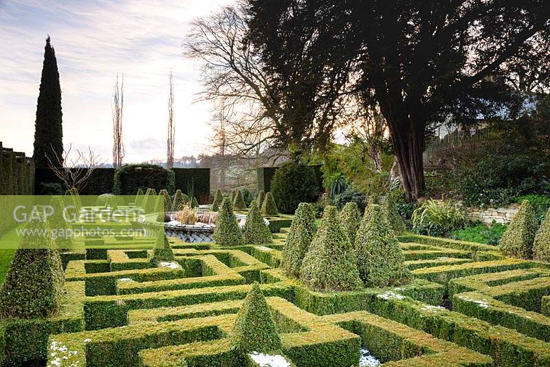 A knot garden of clipped Buxus - Box - with variegated Box pyramids and a central basketwork pond 