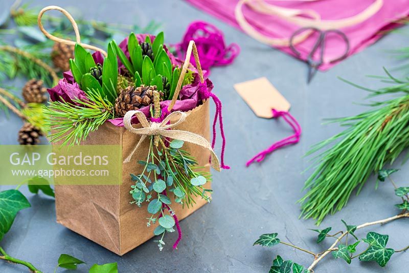 Hyacinth bulbs wrapped as present in brown paper bag, lined with pink tissue paper, boc and Eucalyptus foliage