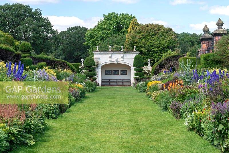 The 90-metre-long twin herbaceous borders with view to Grade II listed alcove at the end. Arley Hall, Cheshire, UK.
