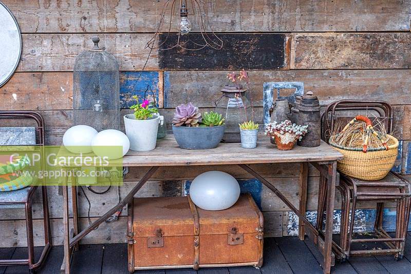 A table in the covered dining area decorated with pots of succulents and various salvaged objects.