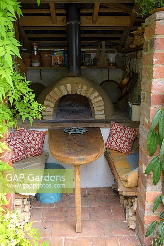 Seating area with a hand built pizza oven in a small courtyard garden.