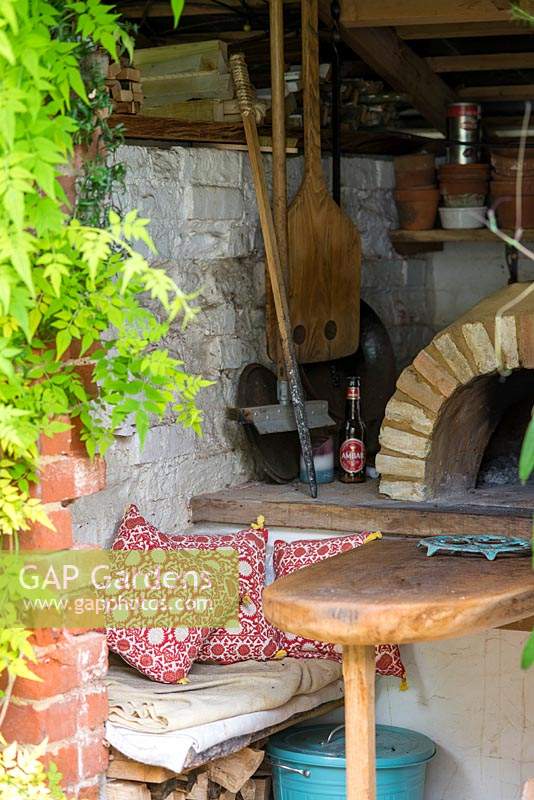 Seating area with a hand built pizza oven in a small courtyard garden. 