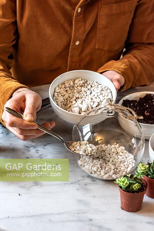 Planting an open terrarium. Step 1 - using a dessert spoon, cover the base with alpine gravel.
