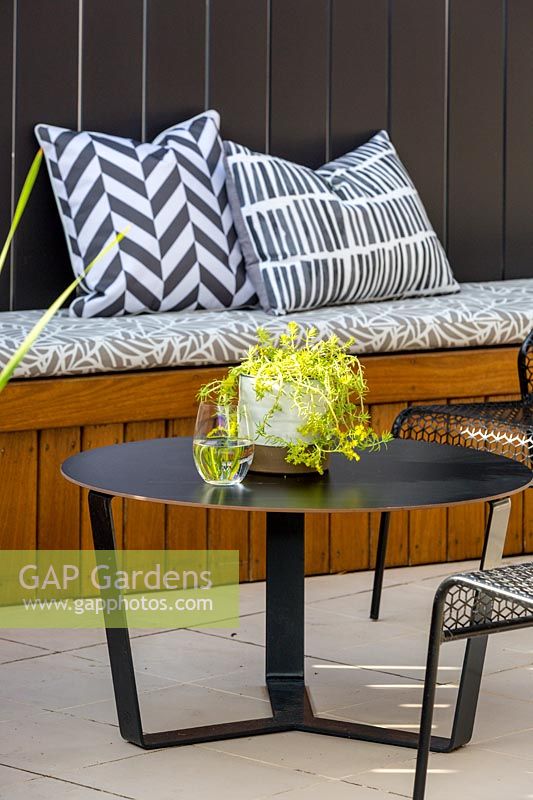 Contemporary style metal table and chairs with a glazed ceramic pot planted with a succulent, Gold Mound.