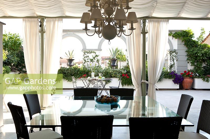 Dining area on veranda under canopy with view onto roof terrace in summer 