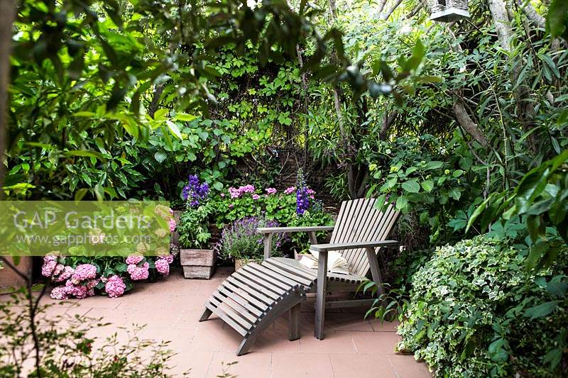 Enclosed patio area with recliner surrounded by mixed planting

