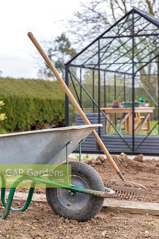 Wheelbarrow and rake for ground preparation in new kitchen garden