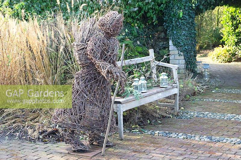 Woven sculpture of woman walking with stick