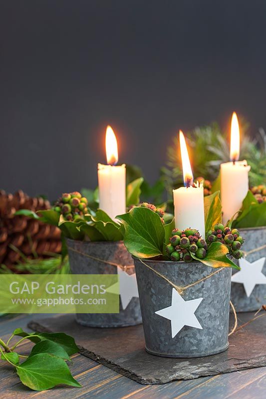 Table decoration featuring candles in miniature galvanised buckets filled with Ivy berries and Bay leaves