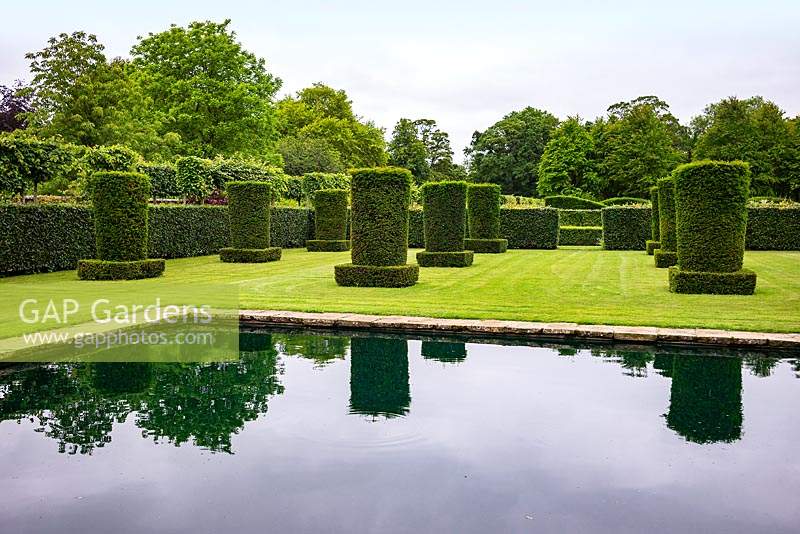 The reflective pool and clipped Yew columns - Taxus baccata - in the Silent Garden at Scampston Hall Walled Garden, North Yorkshire, UK. 